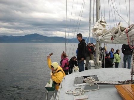 A group of people standing on the deck of a sailboat.