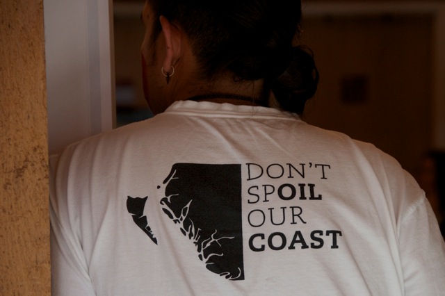 A woman wearing a t - shirt that says don't spoil our coast.