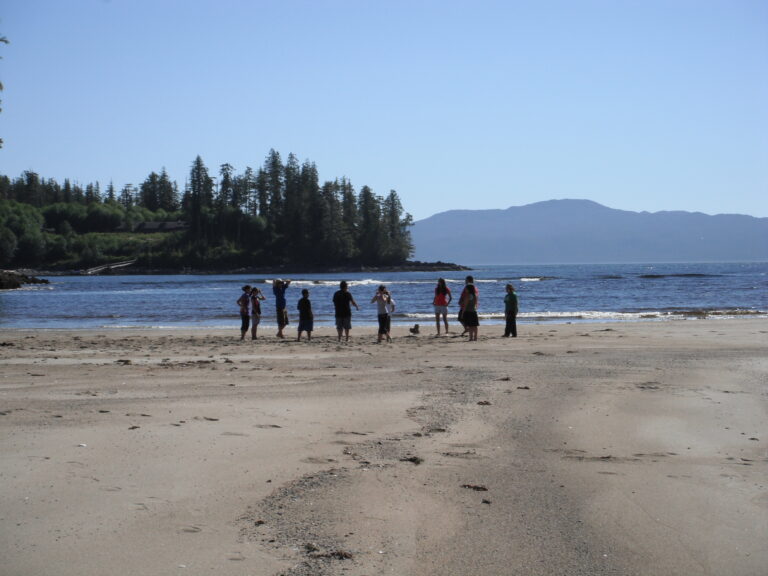 A group of people standing on a sandy beach.
