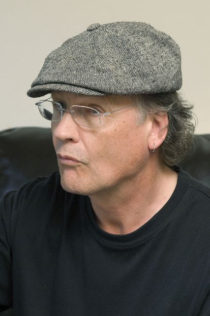 A man wearing glasses and a hat sitting on a couch.