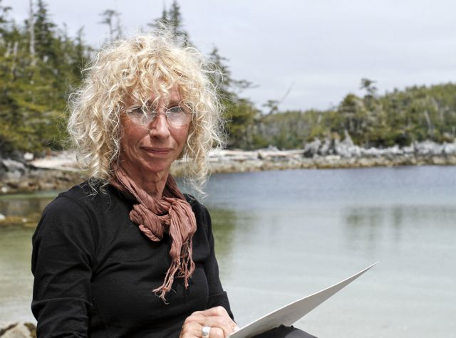 A woman sitting on a beach with a notebook.