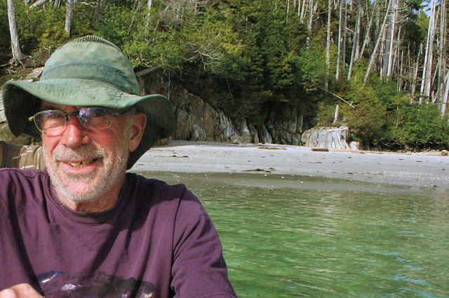 A man in a green hat sitting on a boat in the water.