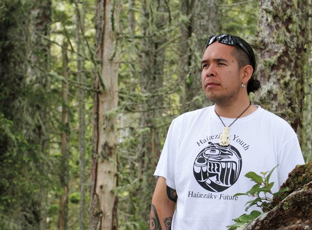 A man in a white shirt standing in the woods.
