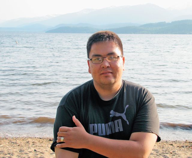 A man standing on a beach next to a body of water.