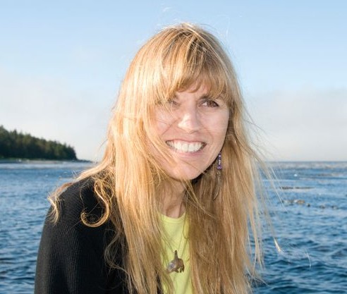 A woman smiling in front of a body of water.