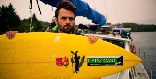 A man holding a yellow surfboard on a boat.