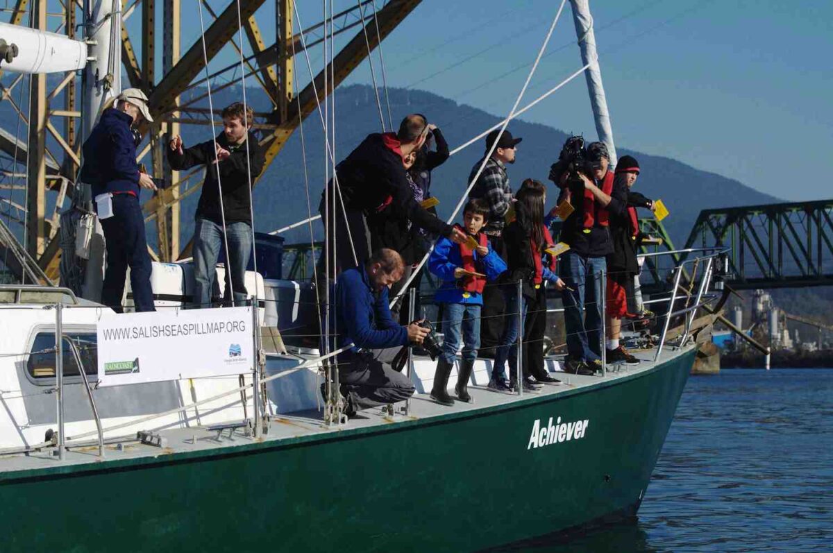 A group of people standing on the deck of a green boat.