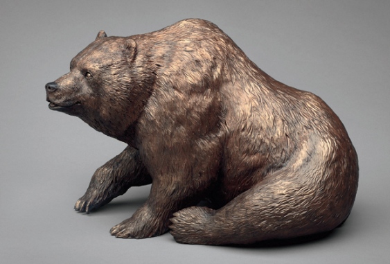 A bronze sculpture of a brown bear sitting down.