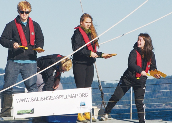 A group of people standing on a sailboat.