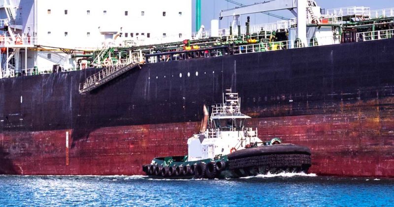A tug lines up beside a massive oil tanker.