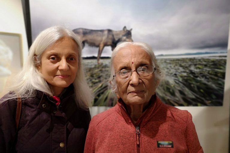 Two people pose in front of Bertie Gregory's photo at One Shot for Coastal Carnivores.