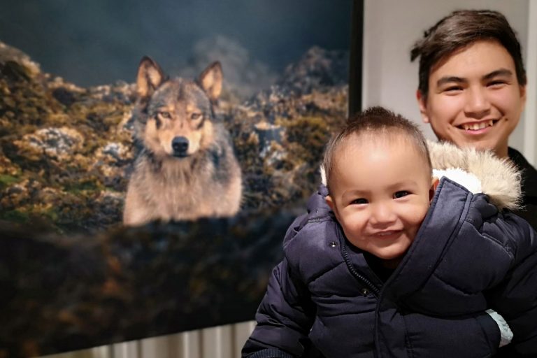 Father and son from Esquimalt nation pose in front of Cristina Mittermeier's photo at One Shot for Coastal Carnivores.