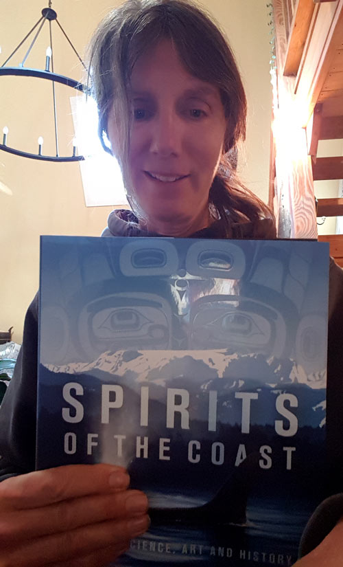 Misty MacDuffee holds up the book Spirits of the Coast.