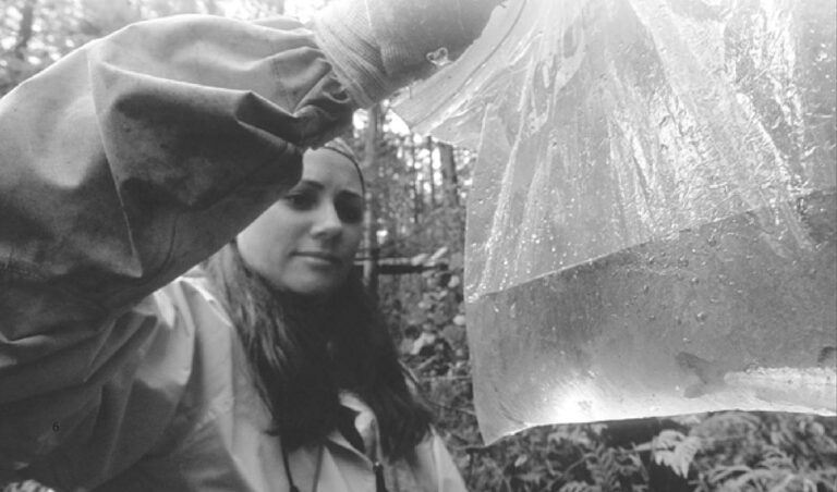 Nicola Temple holds up a ziploc with a small salmon fry in it during field work in the Great Bear Rainforest.