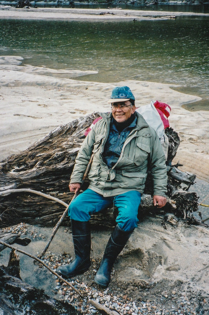Cecil Paul sitting on a stump by the water.