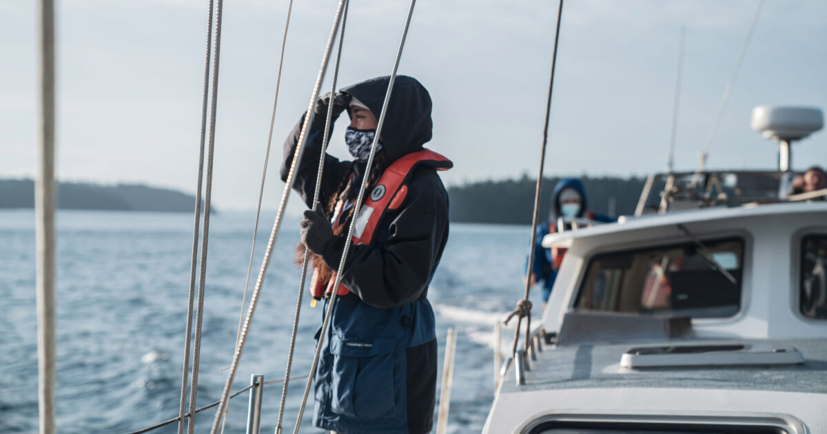 A Salish Sea Emerging Steward stands aboard Achiever looking out.