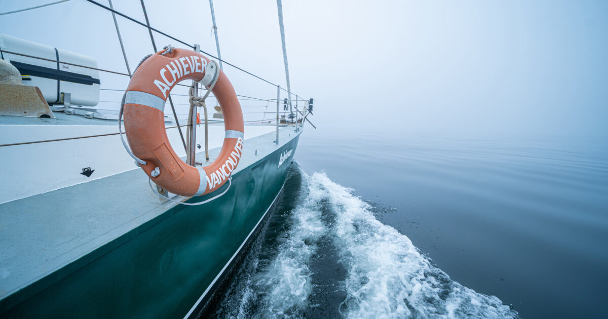 SV Achiever glides through the quiet waters into the fog with small ripples in the water.