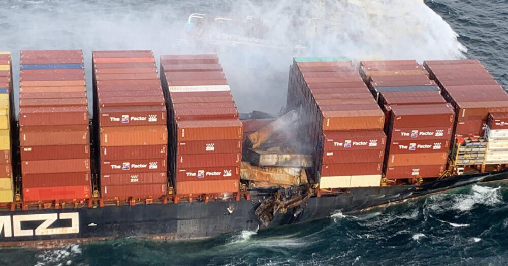 Cargo ship covered in smoke with burned shipping containers