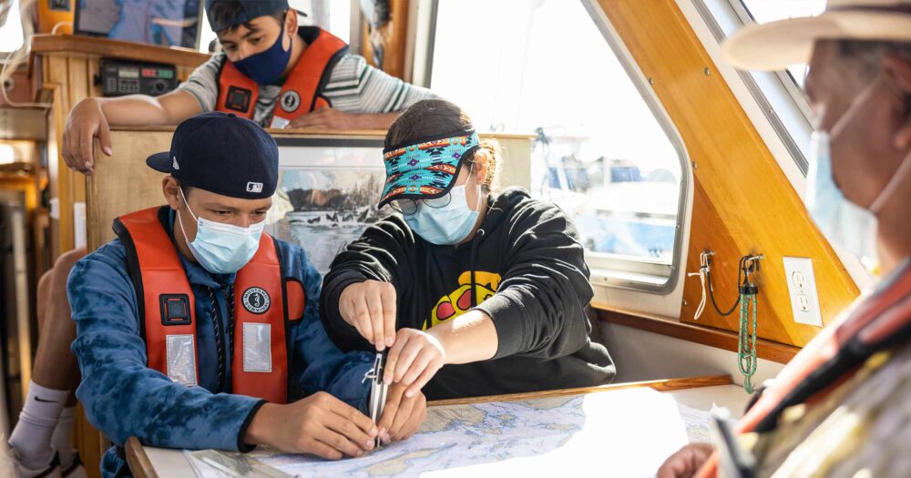 Three students on a boat looking at a map.