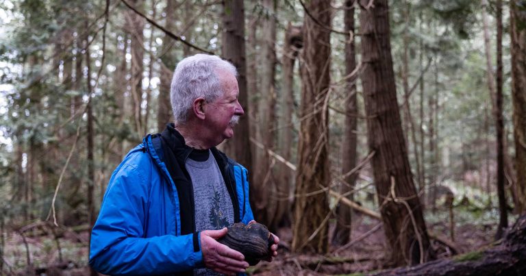 Andy MacKinnon holding a conk fungi standing in a forest.