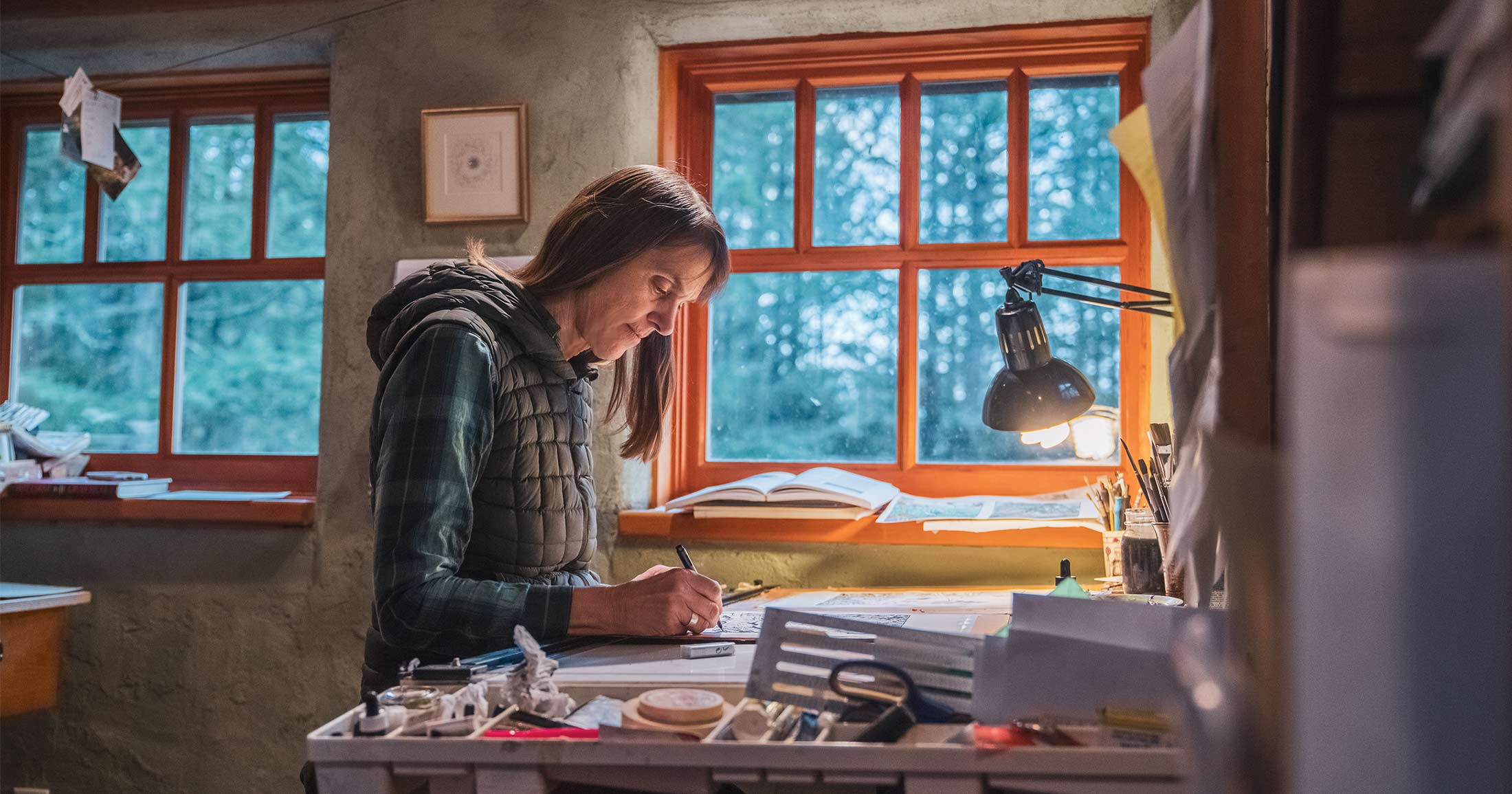 Briony Penn sitting in her studio making art.