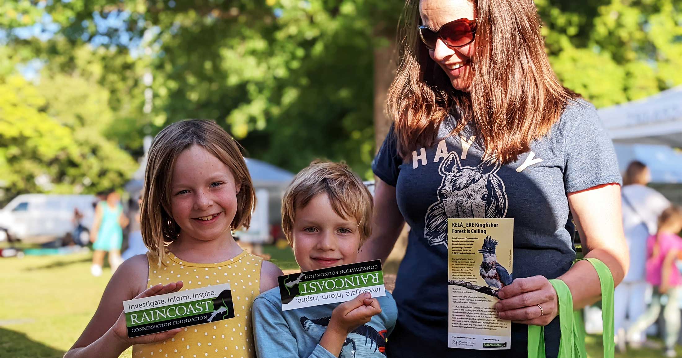 Mother and two children in the sun holding Raincoast printed materials.