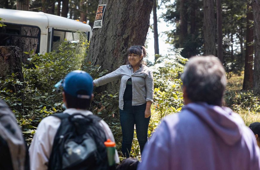 PEPAKIYE standing in front of a crowd of people teaching.