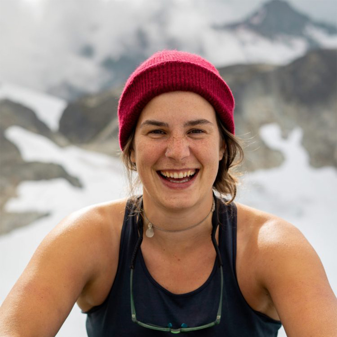 Ali Gladwell wearing a tank top and a toque with a snowy mountain in the background. 