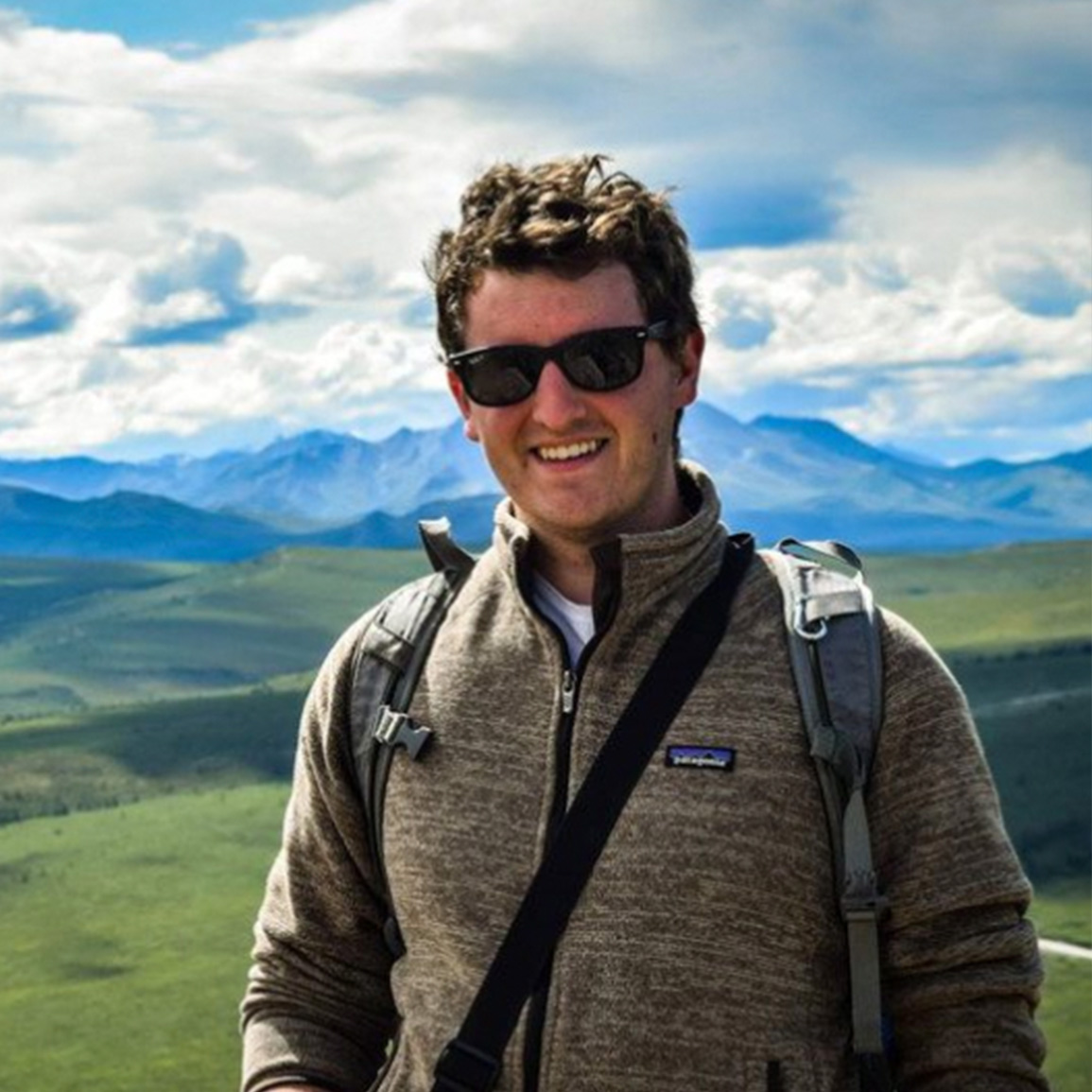Tyler Jessen wearing sunglasses with mountains in the background.