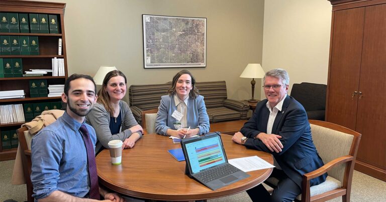 Four people sitting around a round table in a parliamentary office.