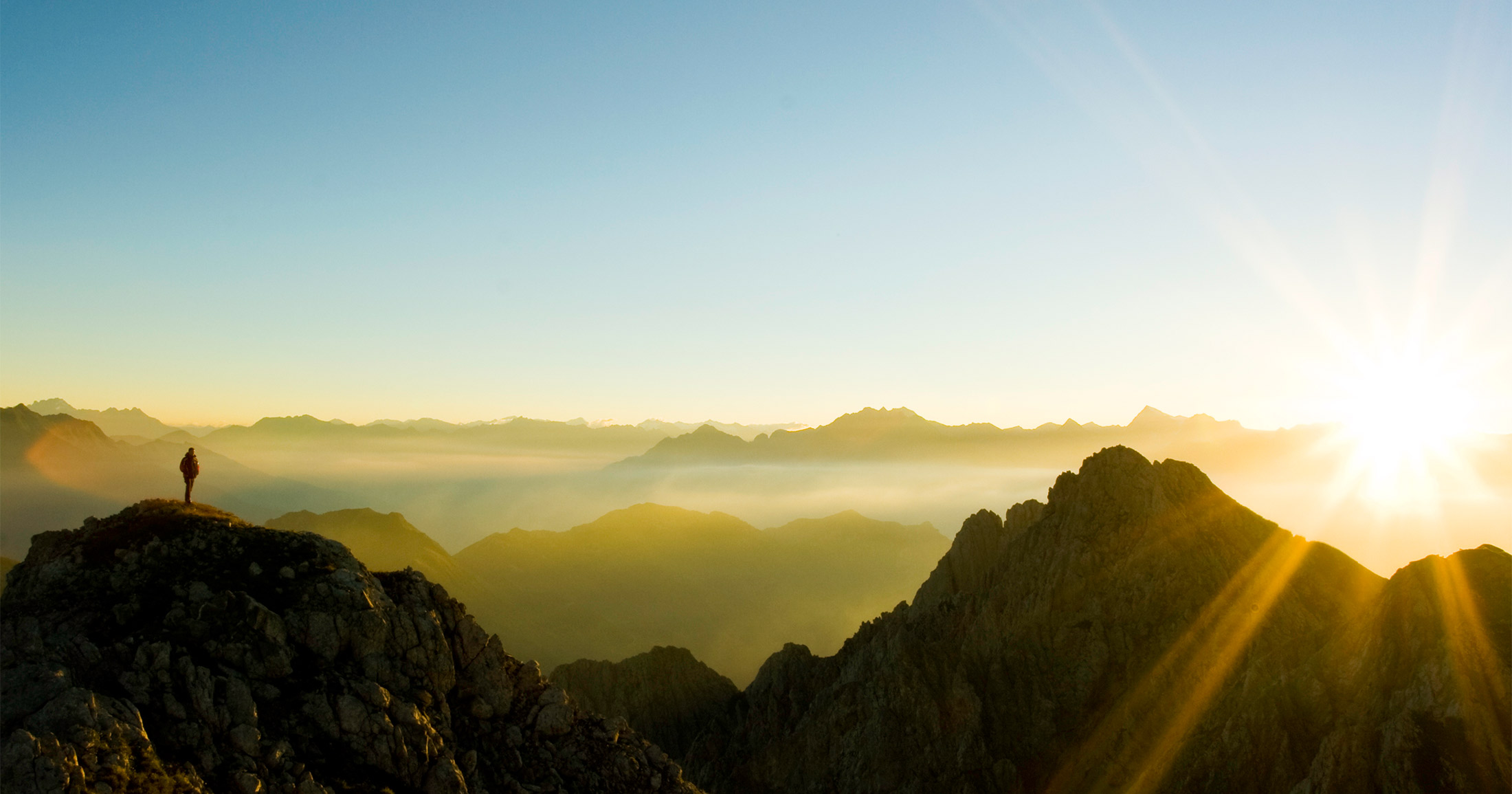 Human standing on the peak of the mountain during a sunset.