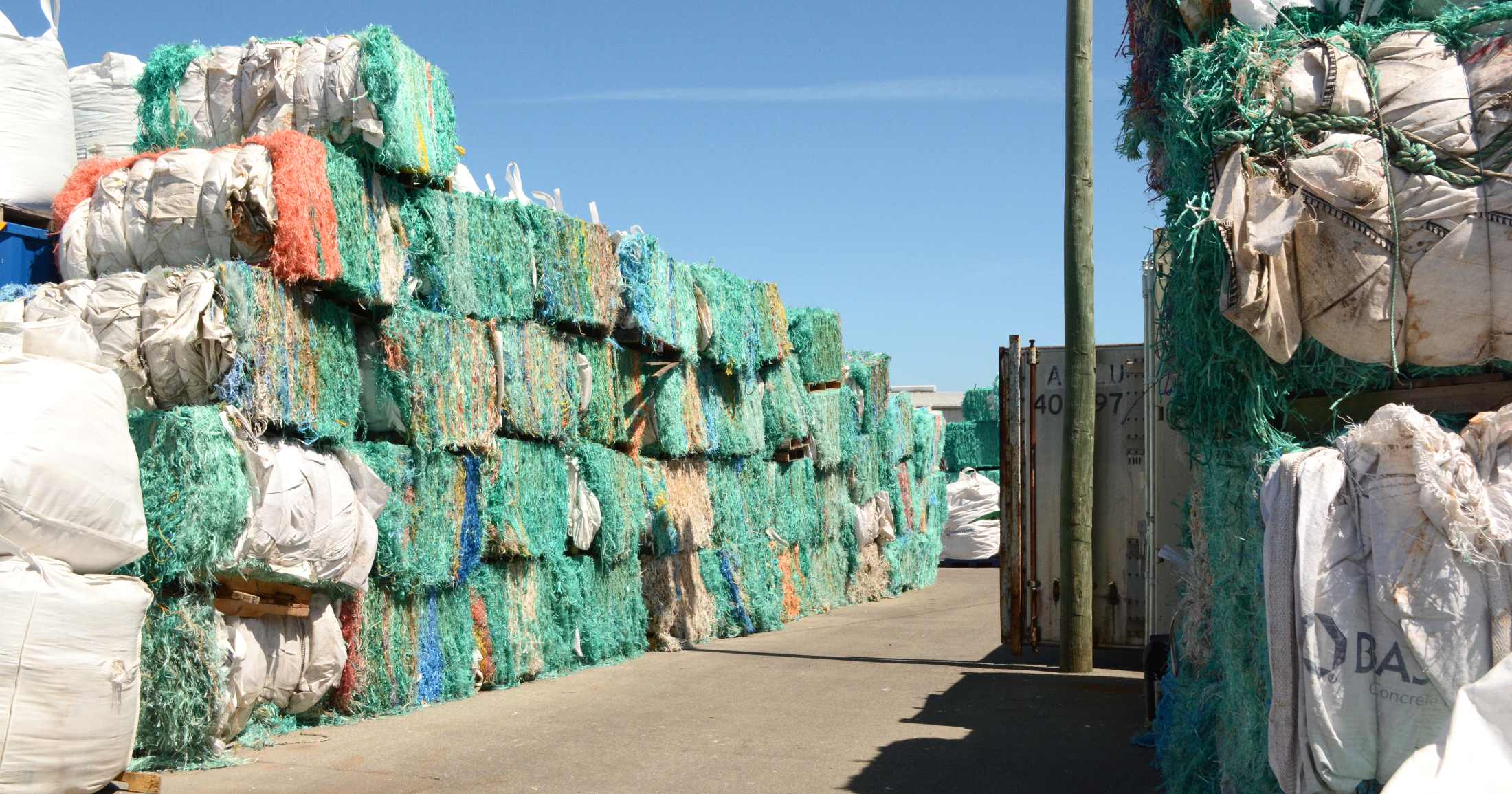 Bales of colorful fishing nets stacked on top of each other in a row.