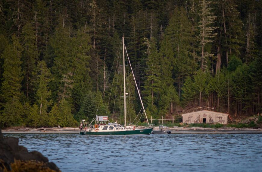 Achiever sits near the shoreline with a forested backdrop.