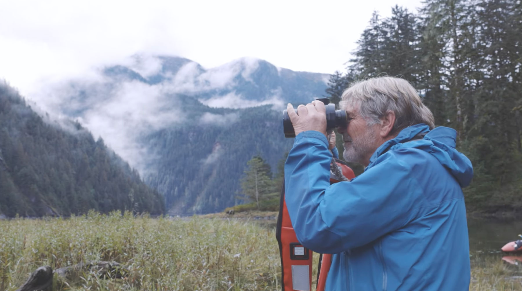 Brian Falconer looks through his binoculars on a misty and foggy day in the Great Bear Rainforest.