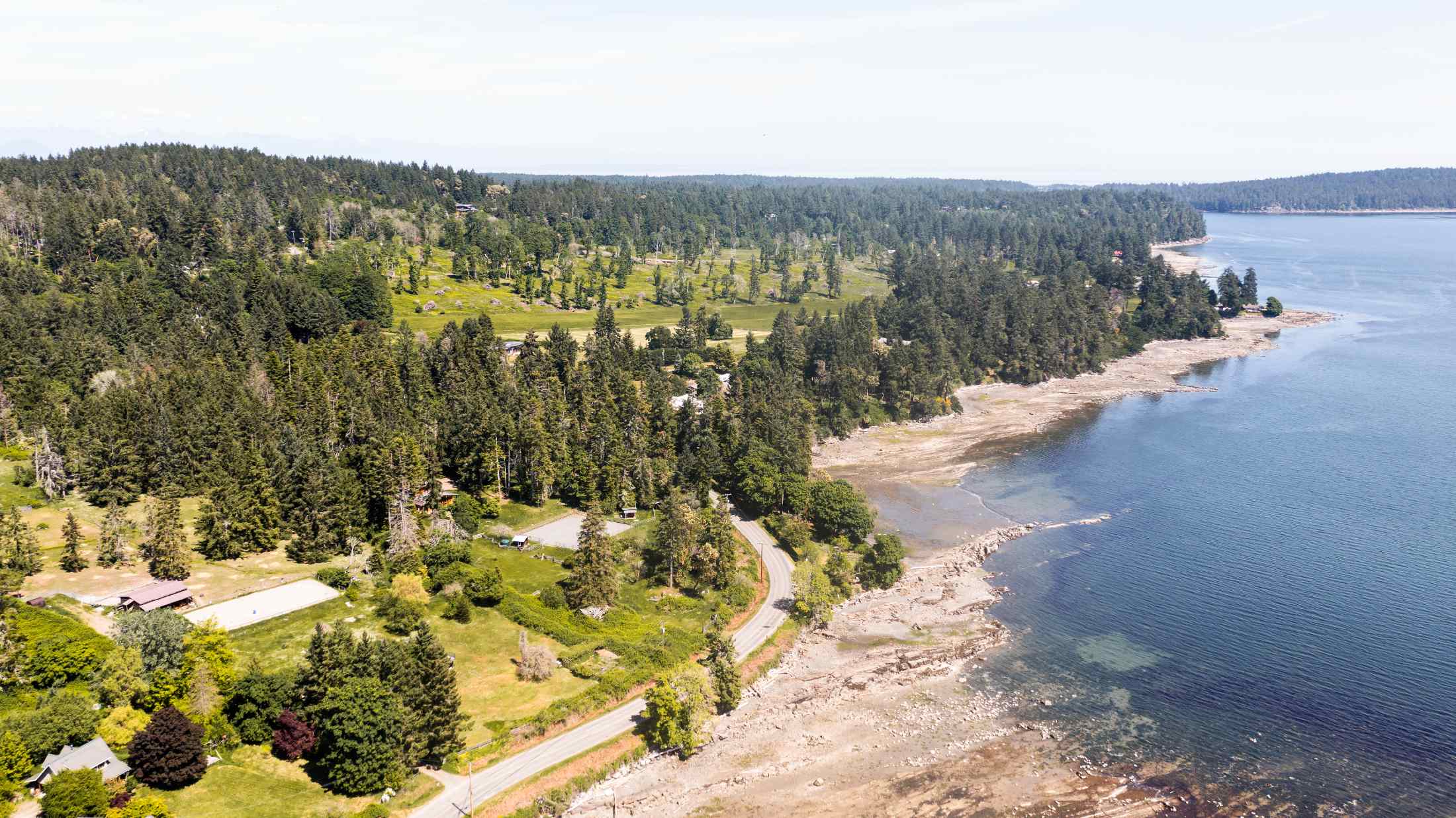 An aerial view of the shoreline where the ocean meets fragmented forested land. 