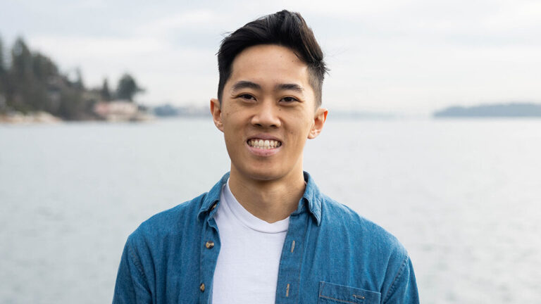 Auston Chhor wearing a blue shirt standing in front of the ocean.