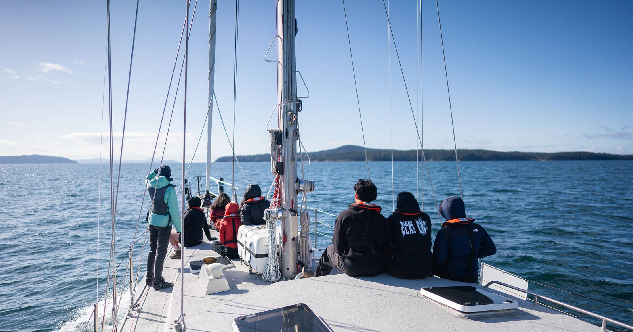 Group of youth sitting on the front of sailboat, Achiever.