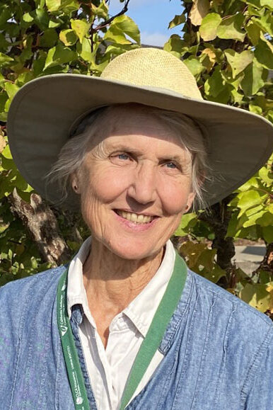 Jane Packard smiles in a blue sweater and sun hat.