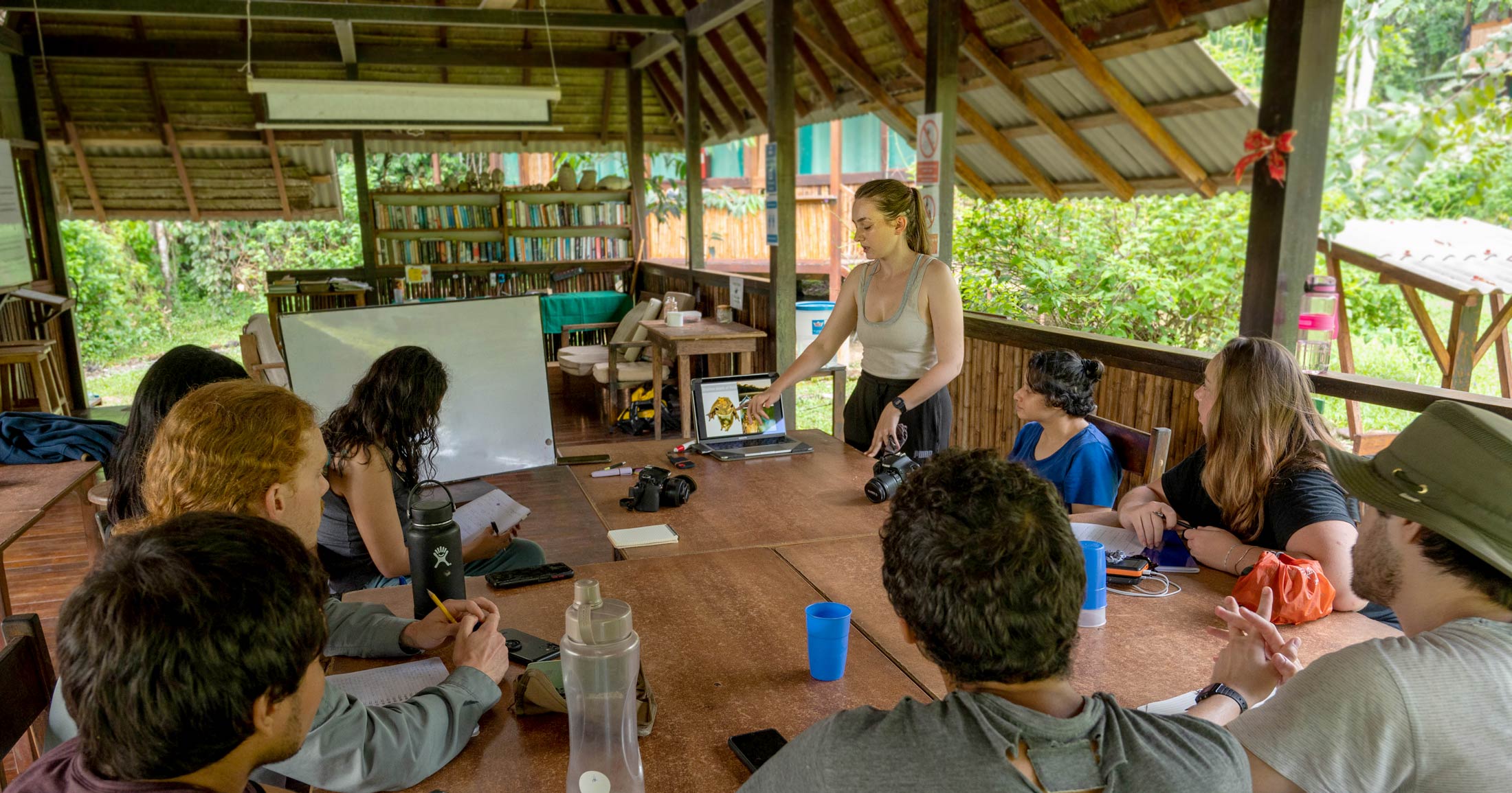 Nicole stands in front of a team and presents her findings.