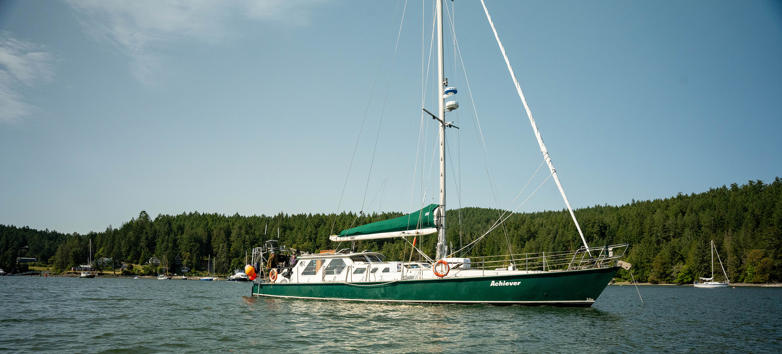 Research vessel Achiever sits on calm water against a blue sky