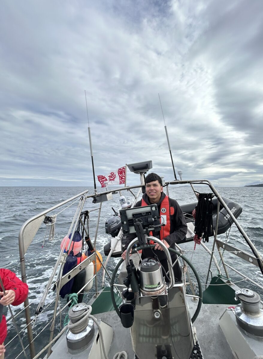 A teenager at the helm of a sailboat