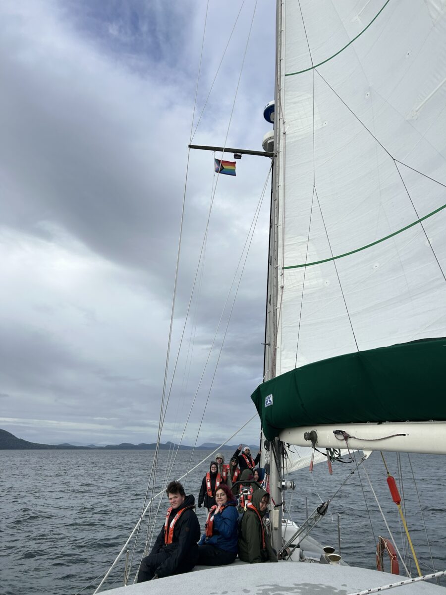 A group sits on the bow of a sailboat