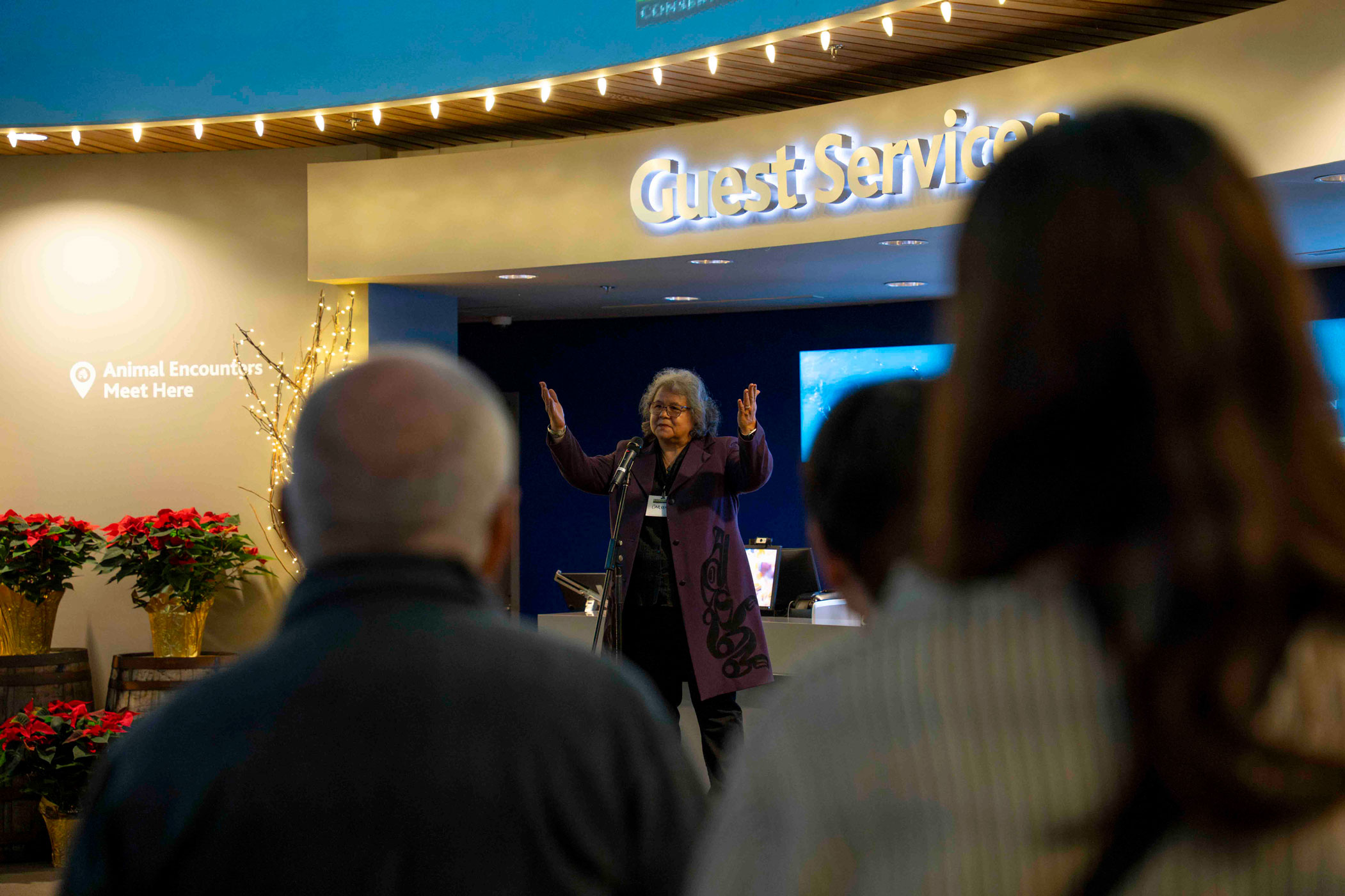 Carleen Thomas from the Tsleil-Waututh Nation is seen through the crowd, standing on stage with her hands raised welcoming attendees.