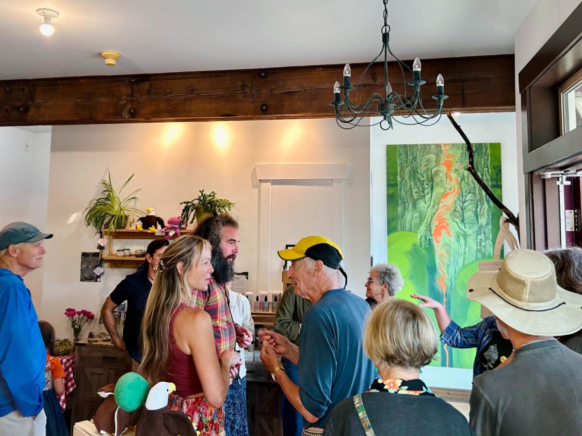 A group of 12 people stand around a room chatting.