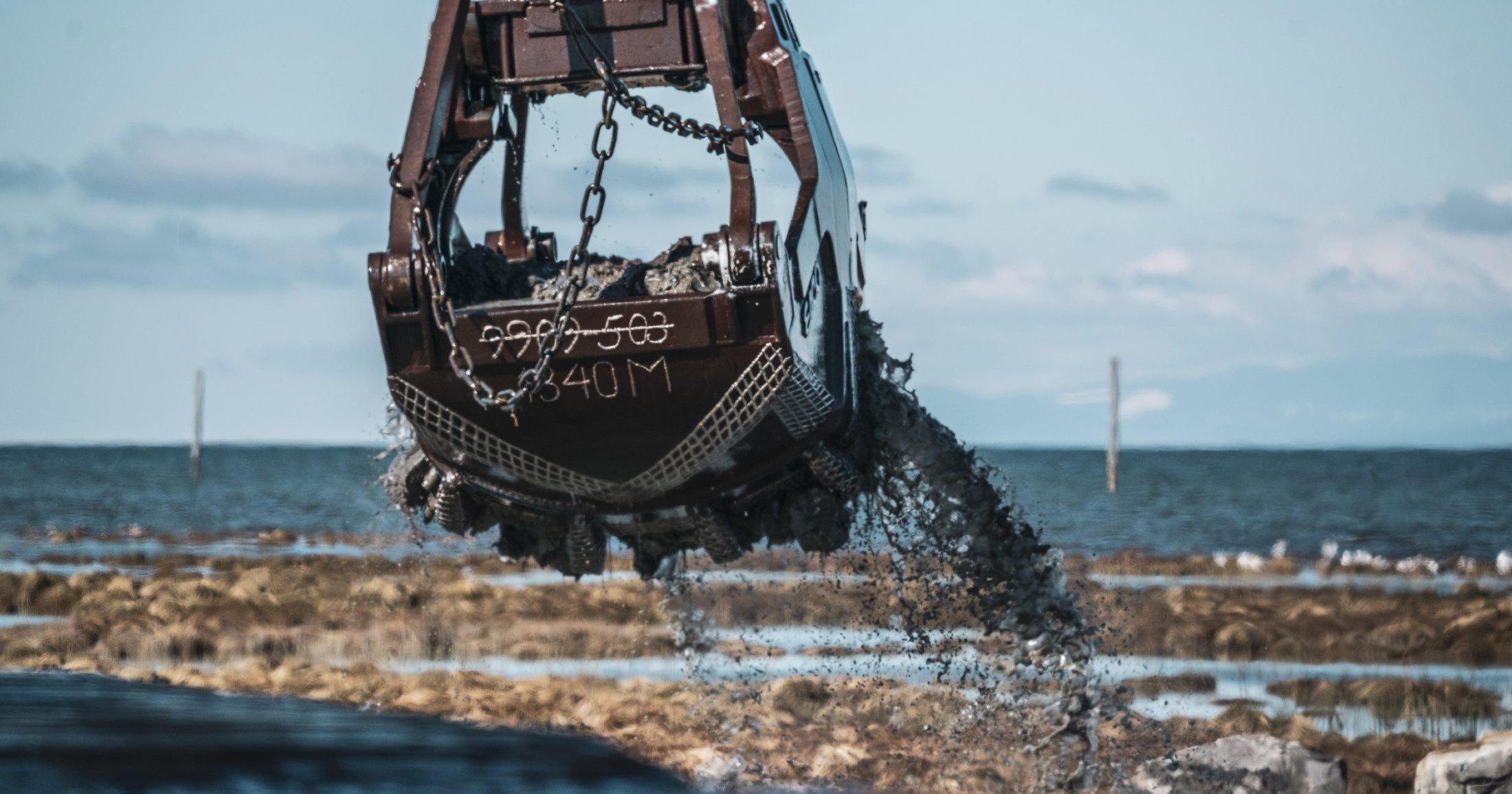 A piece of machinery lifts dirt off the ground as part of habitat restoration.